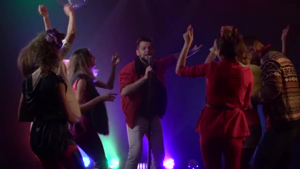 L'homme chante dans un microphone rétro les gens dansent. Fumée de fond. Mouvement lent — Video