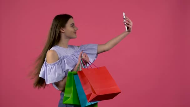 女の子はカラフルなパッケージで selfies を行います。ピンクの背景 — ストック動画