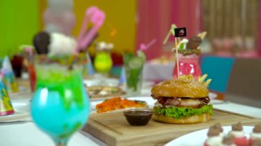 Üzerinde hamburger, pizza ve renkli kokteyller ile şenlikli öğle yemeği.