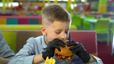 Restoranda hamburger yiyen küçük bir çocuğun yavaş hareketi.