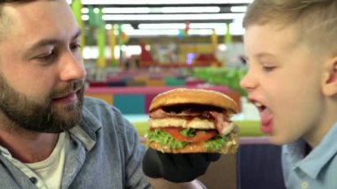 Restoranda hamburger yiyen baba ve oğulun yakın çekimi.