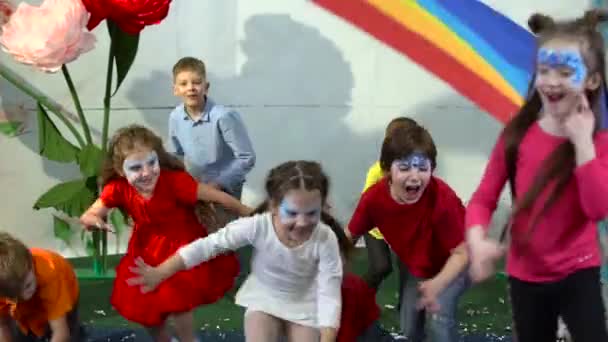 Slow motion of schoolkids running under rainbow cloth at entertainment center. — Stock Video