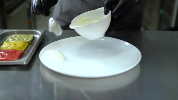 Chef put sauce on white plate spreading it around plate with spatula. — Stock Video