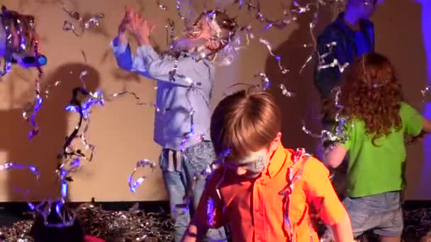 Bailando niños vomitando oropel sobre fondo gris, cámara lenta . — Vídeos de Stock