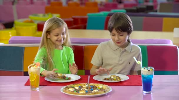 Ευτυχισμένοι φίλοι τρώγοντας πίτσα σοκολάτας στο παιδικό κέντρο ψυχαγωγίας. — Αρχείο Βίντεο