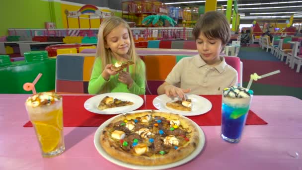 Χαρούμενοι φίλοι τρώγοντας πίτσα σοκολάτας κατά τη διάρκεια του δείπνου στο παιδικό καφέ. — Αρχείο Βίντεο