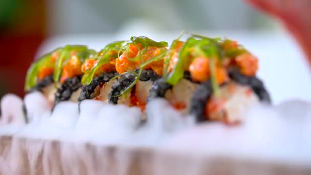 Χέρι με ξυλάκια που λαμβάνουν σούσι σερβίρεται σε κάπνισμα σε ιαπωνικό εστιατόριο. — Αρχείο Βίντεο