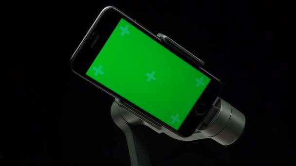 スマートフォン上の緑色の画面を持つステディカムジンバルスタビライザーが回転しています. — ストック動画