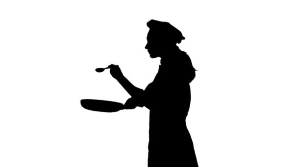 Schwarze Silhouette der Küchenchefin, die mit einem Löffel in der Pfanne rührt. — Stockvideo