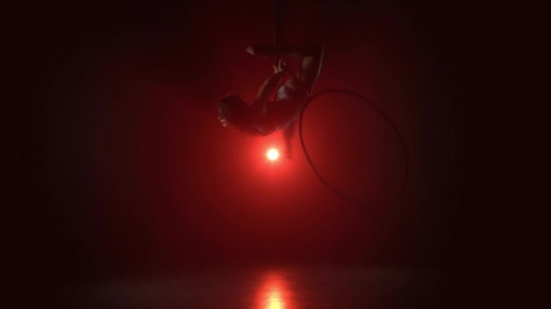 Воздушный акробат на ринге. Молодая девушка выполняет акробатические элементы в воздушном кольце на красном фоне 020 — стоковое видео