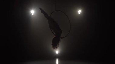 Silhouette Genç beyaz esmer sportif dansçı kadın dengeleyici bej Leotard arka ışık arka arkaya üç ışınları üzerinde hava çember askıda yatıyor 032