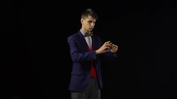 Young male in suit is solving Rubiks Cube in dark. — Stock Video