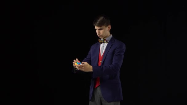 Smart Boy im Anzug löst Rubiks Würfel im Dunkeln. — Stockvideo