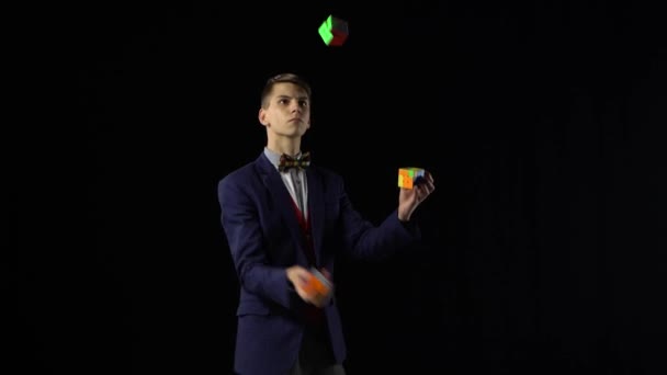 Hombre guapo de traje es malabares Rubiks Cube en la oscuridad . — Vídeo de stock