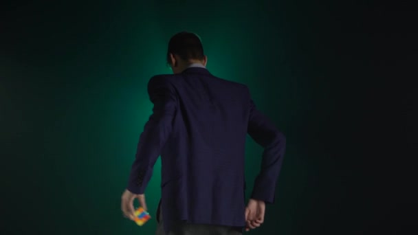 Clever guy in suit is solving Rubiks Cube in dark. — Stock Video