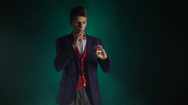 Beau gars en costume résout Rubiks Cube dans l'obscurité . — Video