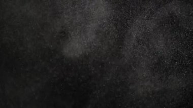 Yüzen farklı büyüklükteki toz parçacıkları siyah arka plan üzerinde uçuyor.