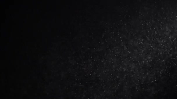 Na černém studiovém pozadí svítí stoupající průhledný prach. — Stock video