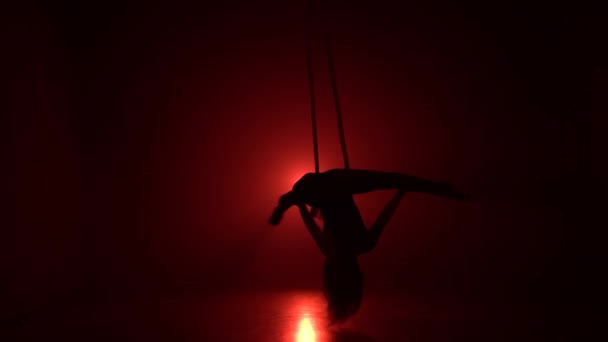 Menina aerialista silhueta fazendo truques acrobáticos e flexíveis em sedas aéreas vermelhas ou tecidos no fundo vermelho 052 — Vídeo de Stock