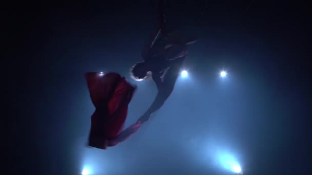 青い光の背景に赤いシルクで空中運動を行う優雅な体操選手 084 — ストック動画