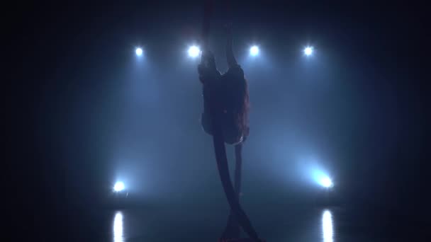 Graceful gymnast performing aerial exercise with red silk on blue light background 085 — Stock Video