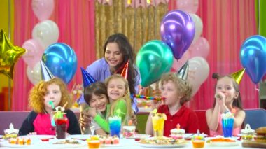 Renkli şapkalı çocuklar anne ve şeytanlarla doğum gününü kutluyor.