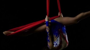 Güzel havacı kız kırmızı arka plan üzerinde kırmızı hava ipek dokuları üzerinde akrobatik ve esnek hileler yapıyor. Yavaş çekim. Closeup. 296