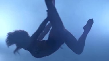 Zarif jimnastikçi mavi ışık arka plan üzerinde kırmızı ipek ile hava egzersiz icra. Yavaş çekim. Closeup. 328