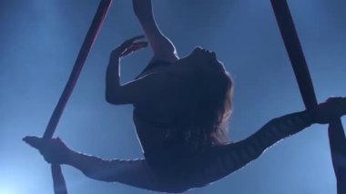 Zarif jimnastikçi mavi ışık arka plan üzerinde kırmızı ipek ile hava egzersiz icra. Yavaş çekim. Closeup. 336