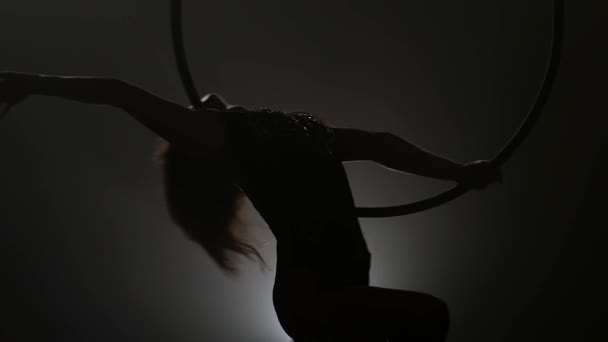 Силуэт Молодая девушка выполняет акробатические элементы в воздушном кольце. Медленное движение. Крупный план. 250 — стоковое видео