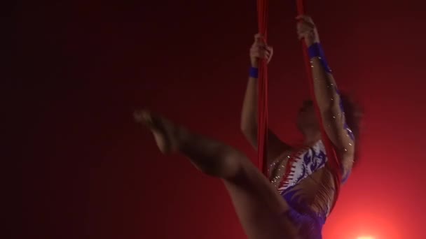 Красивая aerialist девушка делает акробатические и гибкие трюки на красной воздушной шелковой ткани на красном фоне. Медленное движение. Крупный план. 289 год — стоковое видео