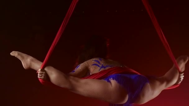 Красивая aerialist девушка делает акробатические и гибкие трюки на красной воздушной шелковой ткани на красном фоне. Медленное движение. Крупный план. 292 год — стоковое видео