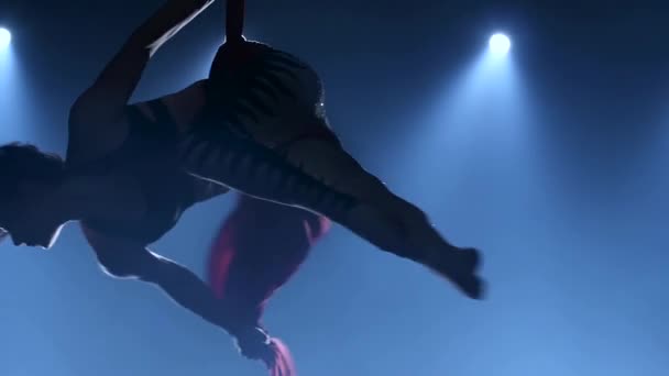 Грациозная гимнастка, выполняющая воздушные упражнения с красным шелком на синем светлом фоне. Медленное движение. Крупный план. 335 год — стоковое видео