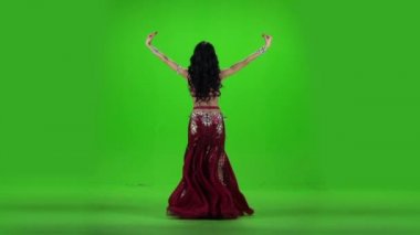 Arkada duran bir kadın dansı dansı yapıyor. Yeşil arka plan. Yavaş çekim