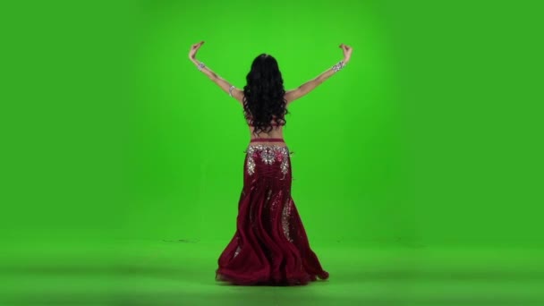 Жінка, що стоїть, танцює танець живота. Зелений фон. Повільний рух — стокове відео