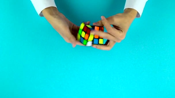 Ukrajna, Dnipro 20 február 2019: mans kezében gyorsan oldja meg a Rubiks Cube a kék háttér. — Stock videók