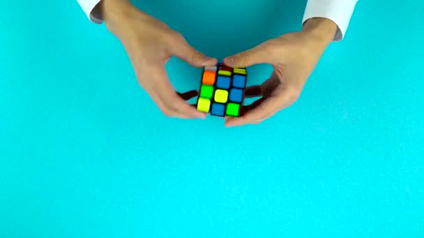 Ukraina, Dnipro 20 lut 2019: Mężczyźni ręce Rozwiązywanie Rubiks Cube szybko na niebieskim tle. — Wideo stockowe