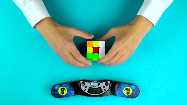 Ukraina, Dnipro 20 lut 2019: ręce osoby rozwiązujące Rubiks Cube, czas nagrywania na stoper. — Wideo stockowe