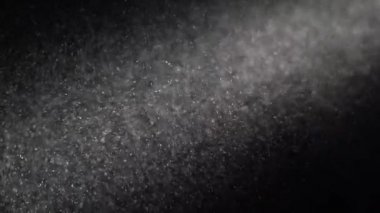 Toz parçacıkları siyah arka planda parlıyor.