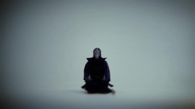 Samuray kendo oturur ve beyaz bir odada meditasyon. Çekimi yakınlaştırmayı kapatmak için orta.