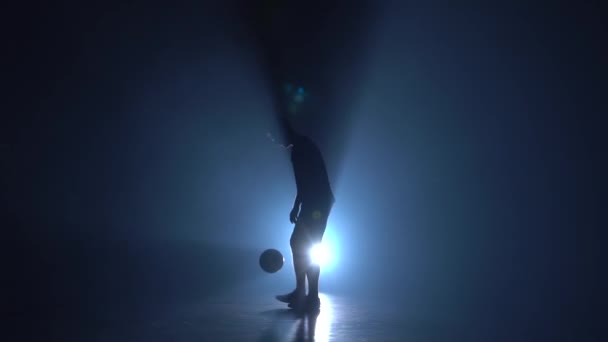 Fußball-Kür. Silhouette eines Freestylers im Studio gegen blaues Scheinwerferlicht. Zeitlupe — Stockvideo
