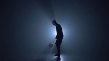 Mavi spot karşı stüdyoda futbol freestyler silueti. Yavaş çekim