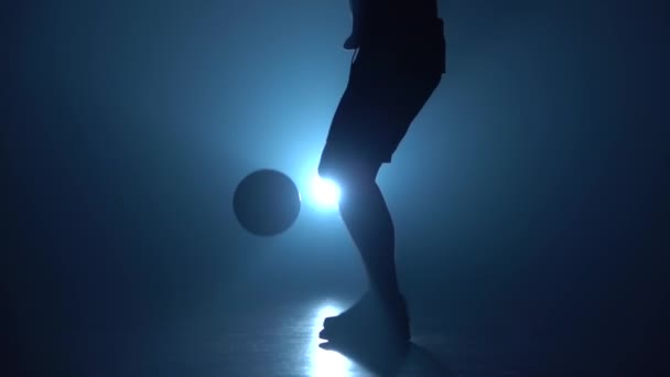 Primer plano jugadores de fútbol pies relleno bola contra el centro de atención azul. Movimiento lento — Vídeo de stock