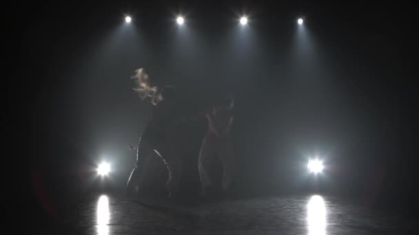 스튜디오에서 스포트라이트에 대한 어둠 속에서 카포에이라를 연습하는 여성. — 비디오