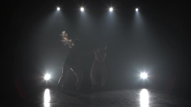 Frauen üben Capoeira im Dunkeln gegen Scheinwerferlicht im Studio. — Stockvideo