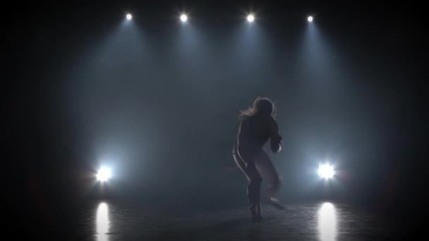 Femme aux cheveux longs pratiquant la capoeira dans l'obscurité contre les projecteurs en studio . — Video