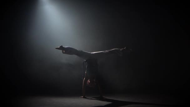 カーリー乙女はスタジオでスポットライトに対して暗闇の中でカポエイラを練習. — ストック動画