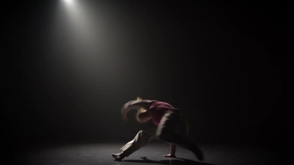 Mujer practicando capoeira en la oscuridad bajo el foco de atención en el estudio . — Vídeos de Stock