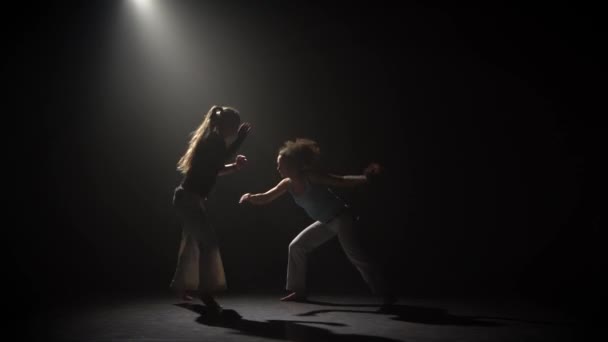 Capoeira en la oscuridad bajo el foco en el estudio sobre fondo negro — Vídeo de stock