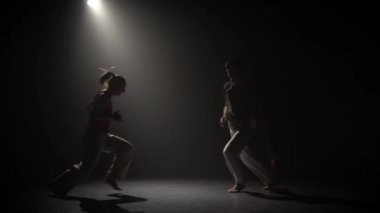 Genç çift stüdyoda spot altında karanlıkta capoeira pratik